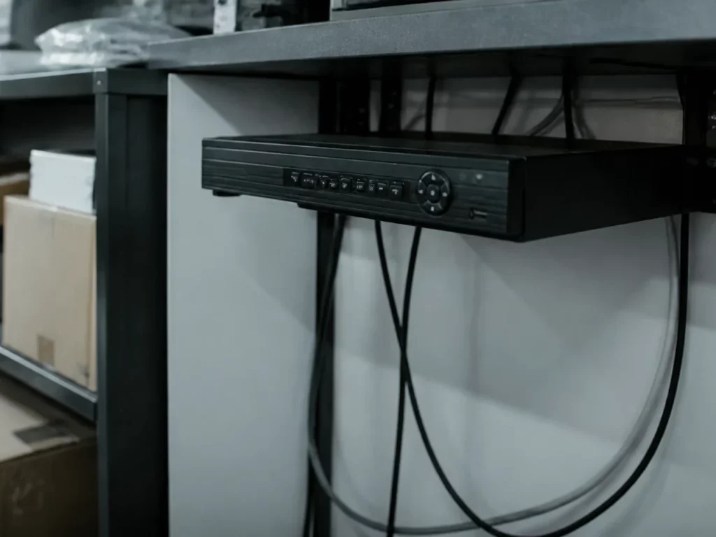 Enregistreur vidéo posé sous un comptoir d’arrière-boutique, accès ouvert à toute l’équipe