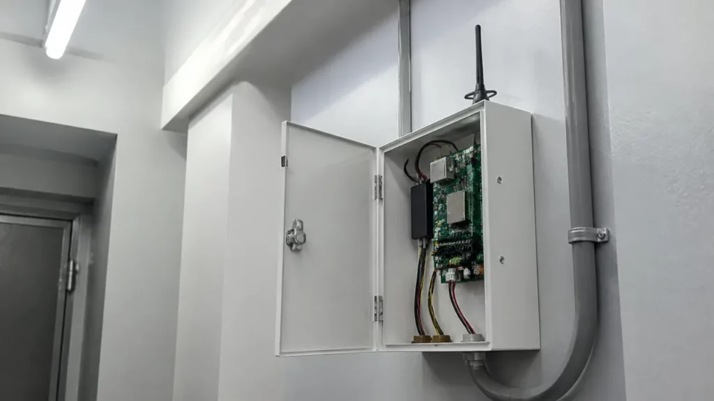 Coffret de centrale d’alarme ouvert dans un local technique, module de transmission et petite antenne fixés à côté