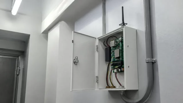 Coffret de centrale d’alarme ouvert dans un local technique, module de transmission et petite antenne fixés à côté