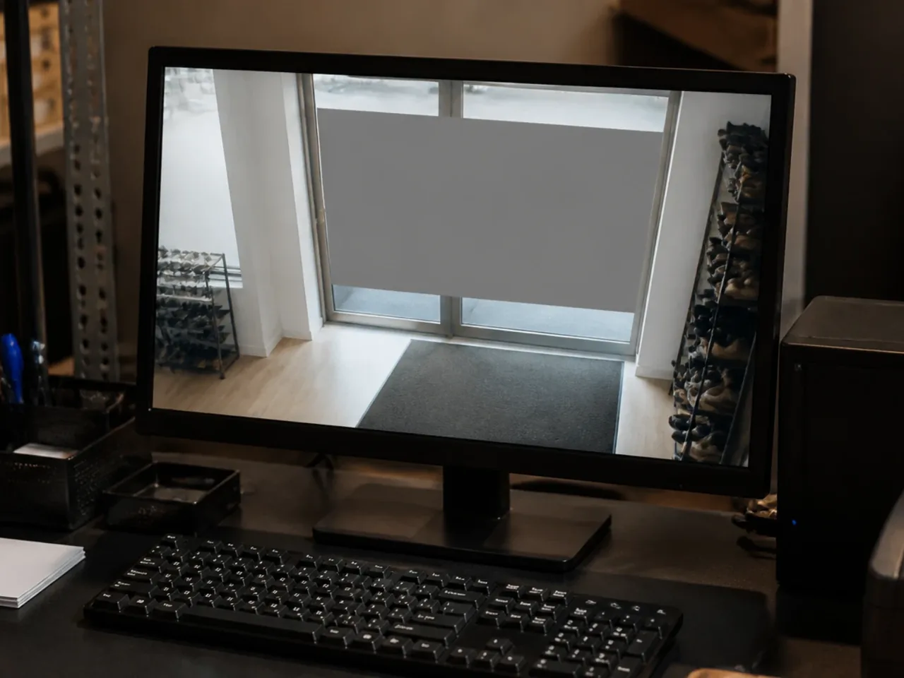 Écran de vidéosurveillance montrant l'entrée d'une boutique avec une zone grisée masquant la vitrine et la rue